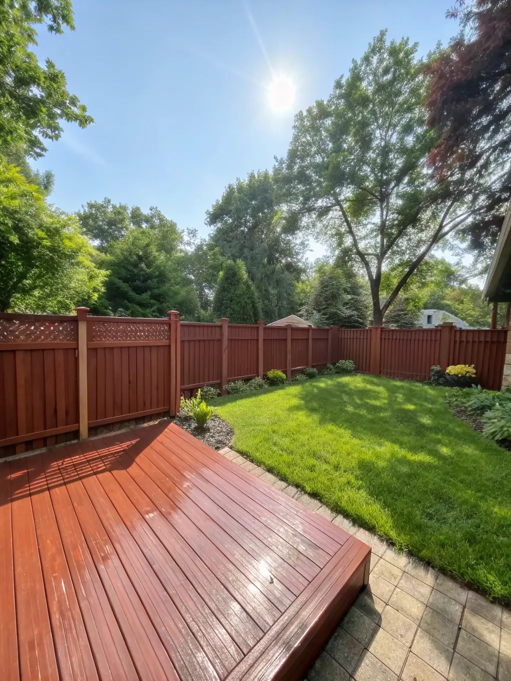 A beautifully paved patio with a wooden deck and decorative fencing, representing Birmingham Gardeners' construction and structural features services.